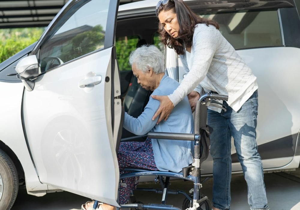 Asian senior woman patient sitting on wheelchair prepare get to her car.