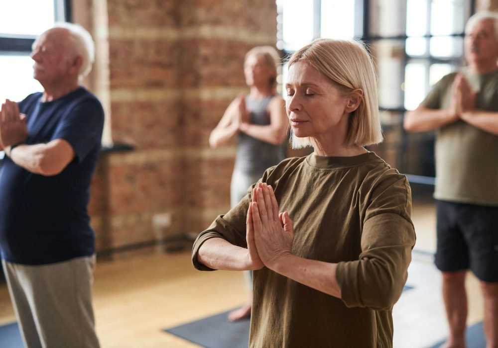 Group of mature men and women keeping hands put together by chest